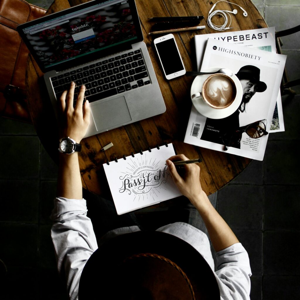 pexels-photo-57690-57690 Top view of a creative workspace with laptop, coffee, and hand lettering for design inspiration.